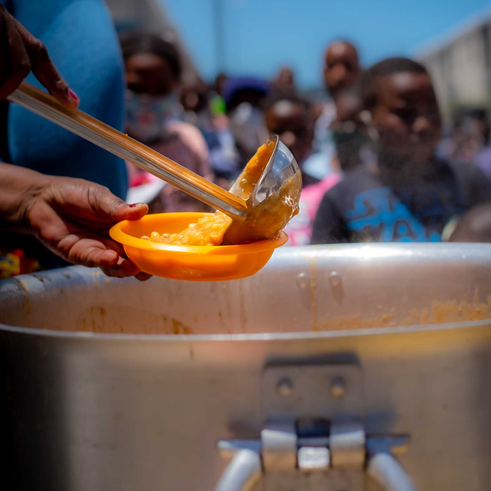a giant spoon serving hot food out of a soup kitchen pot creating awareness for charities to donate to for christmas